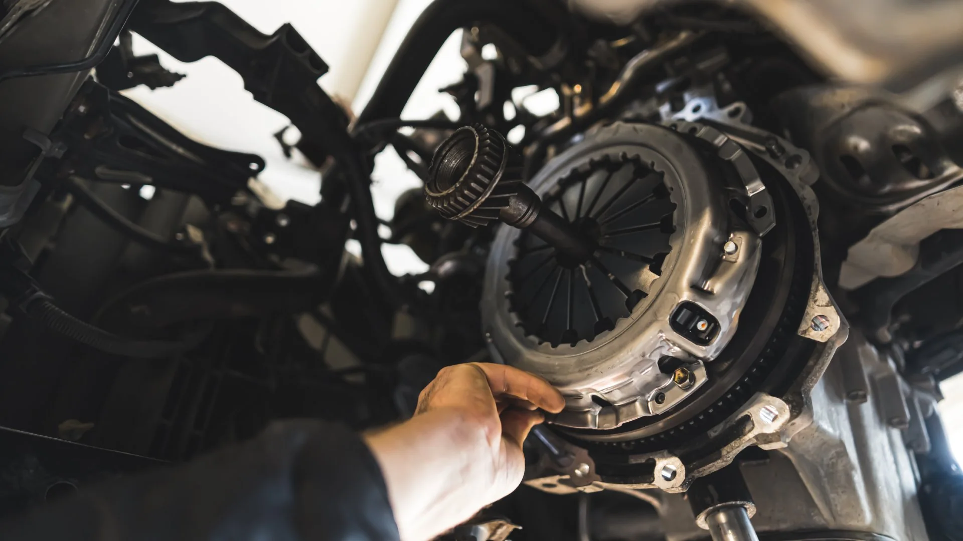 Mechanic adjusting a clutch assembly beneath a vehicle